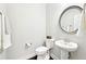 Elegant powder room featuring pedestal sink, decorative mirror and pristine white fixtures at 504 Taymack Farm Ct, Woodstock, GA 30188