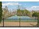 Community tennis courts with players, surrounded by trees, a fence, and a black fence in the foreground at 504 Taymack Farm Ct, Woodstock, GA 30188