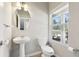 Half bathroom features a pedestal sink, toilet, and window offering natural light at 780 Mccart Rd, Lawrenceville, GA 30045