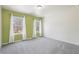 Bright bedroom with a light green accent wall and two windows dressed with long, white curtains at 780 Mccart Rd, Lawrenceville, GA 30045