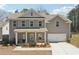 Charming two-story home featuring a welcoming front porch, attached garage, and neutral siding against a backdrop of mature trees at 780 Mccart Rd, Lawrenceville, GA 30045