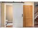 A partially-open barn door reveals a toilet and striped bathmat in this updated bathroom with warm neutral walls at 4 Quail Run, Decatur, GA 30035