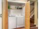 A closet featuring folding shutter doors and containing a stacked washer and dryer next to wood stairs at 4 Quail Run, Decatur, GA 30035