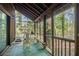 Relaxing screened porch with wooden floors overlooks lush trees, featuring a dining table, grill, and green rug at 4 Quail Run, Decatur, GA 30035