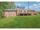 Expansive green backyard featuring a brick home with a wooden deck and stairs at 567 Shiloh Nw Rd, Kennesaw, GA 30144