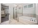 Bright bathroom featuring a shower and soaking tub with white tile and shutters at 1599 Benham Dr, Snellville, GA 30078