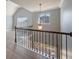 Upstairs hallway featuring hardwood floors, wrought iron decorative railing, and modern lighting at 7686 Brazos Trl, Fairburn, GA 30213