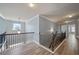 Upstairs hallway with wood-look floors, wrought iron railings, crown molding, and view of a staircase and landing at 7686 Brazos Trl, Fairburn, GA 30213