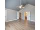 Bedroom with vaulted ceiling, ceiling fan, neutral walls, wood-look floors, and view of ensuite bathroom at 7686 Brazos Trl, Fairburn, GA 30213