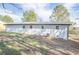 Back exterior of home with a metal roof, white painted brick and green grass with an AC unit outside at 226 Lipham St, Bowdon, GA 30108