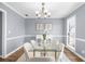 Elegant dining room with modern glass table, white chairs, and soft, neutral decor at 310 Mulberry Manor Ct, Johns Creek, GA 30005