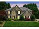 Charming two-story home featuring manicured landscaping, lush lawn and mature trees at dusk at 2115 Brook Pond Ct, Alpharetta, GA 30005