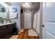 Well-lit bathroom with a dark vanity, wood floors, decorative clocks, and a shower with white curtains at 2376 Allman Dr, Jonesboro, GA 30236