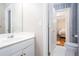 Bathroom featuring a white vanity and blue patterned wallpaper, conveniently located next to a bedroom at 720 First Cotton Dr, Powder Springs, GA 30127