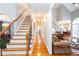 Hallway with staircase, wood floors, and views into the living and dining areas, connecting the home's spaces at 720 First Cotton Dr, Powder Springs, GA 30127