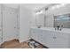 Bright bathroom featuring double sinks, white cabinets, a large mirror and wood look floors at 12 Ridgeline Nw Way, Cartersville, GA 30121