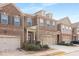 Townhome exterior displaying brick facade, attached garages, and manicured landscaping under a bright sky at 2286 Emerald Sky Dr, Smyrna, GA 30080