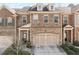 Exterior of a brick townhome featuring a two-car garage, covered entrance, and well-maintained landscaping at 2286 Emerald Sky Dr, Smyrna, GA 30080