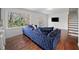 Cozy living room with a plush blue sofa, hardwood floors, large windows, and access to stairs and a modern kitchen at 2717 Hedgewood Nw Dr, Atlanta, GA 30311
