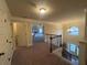 Upstairs hallway with wood and wrought iron banister, carpeted floor, and view of bedroom through doorway at 949 Nevis Way, Mcdonough, GA 30253