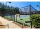 Community tennis court surrounded by a black chain-link fence and tall trees, offering a great recreational amenity at 5002 Davenport Pl, Roswell, GA 30075