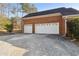Three-car garage of brick house, providing ample parking and storage space with a paved driveway and green shrubs at 4741 Covenant Way, Powder Springs, GA 30127
