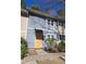 Two-story townhome with light blue siding and white trim with overgrown front yard and boarded front door at 524 Northridge Crossing Dr, Atlanta, GA 30350