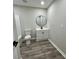Modern bathroom featuring a round mirror, white vanity, toilet, and gray luxury vinyl plank flooring at 295 Lamden Ct, Lawrenceville, GA 30046