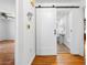 Hallway featuring hardwood floors, a sliding barn door, and an open view into a bright white bathroom at 750 Parkway Se Dr, Smyrna, GA 30080