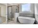 Modern bathroom features a soaking tub, glass shower, and gray tiling for a sleek aesthetic at 209 Haverling Pass, Hampton, GA 30228