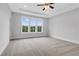 Spacious bedroom with soft carpet, tray ceiling, and large windows offering natural light and a view at 587 Red Clay Farm Ln, Suwanee, GA 30024