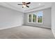 Bedroom featuring soft carpet, a tray ceiling, and a set of sun-drenched, energy-efficient windows at 587 Red Clay Farm Ln, Suwanee, GA 30024
