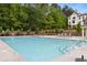 Community pool with lounge chairs, mature trees, and view of residential home in background at 587 Red Clay Farm Ln, Suwanee, GA 30024