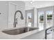A stylish stainless steel kitchen sink is set into a light countertop with a view to the outside at 587 Red Clay Farm Ln, Suwanee, GA 30024