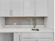 Wet bar features white cabinets, a modern sink and faucet, and a stylish backsplash at 587 Red Clay Farm Ln, Suwanee, GA 30024