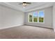 A carpeted bedroom with multiple windows and a tray ceiling offers space and natural light at 557 Red Clay Farm Ln, Suwanee, GA 30024