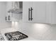 This is a detailed view of a kitchen with white cabinets, black hardware, and a stainless steel range hood at 557 Red Clay Farm Ln, Suwanee, GA 30024