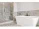 A modern bathroom features a soaking tub and a glass enclosed shower with gray marble style tile at 577 Red Clay Farm Ln, Suwanee, GA 30024