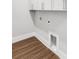 A laundry room features new, dark laminate flooring and white cabinets at 577 Red Clay Farm Ln, Suwanee, GA 30024