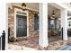 Inviting front porch features a black front door, brick, and classic columns at 475 Letchas Ln, Alpharetta, GA 30009