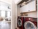 Laundry room with wine-colored appliances, white cabinetry, and view to main bedroom at 475 Letchas Ln, Alpharetta, GA 30009