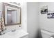 Simple bathroom featuring white sink, classic mirror, with partial view of toilet and nearby window at 8834 Applegate Ln, Atlanta, GA 30350