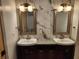 Bathroom featuring dual sinks, large mirrors, and marble patterned tiling at 11637 Brown Bridge Rd, Covington, GA 30016