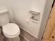 Close-up of a toilet, a shelf, and a toilet paper holder with wood-look floors at 11637 Brown Bridge Rd, Covington, GA 30016