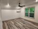 Bright bedroom featuring wood-look floors, a ceiling fan, and a large window showcasing the verdant outdoors at 11637 Brown Bridge Rd, Covington, GA 30016