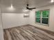 This bedroom has light walls, wood-look flooring, a modern ceiling fan, and a view of the trees outside at 11637 Brown Bridge Rd, Covington, GA 30016