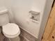 A clean, standard white toilet with a shelf and toilet paper holder against a white wall at 11637 Brown Bridge Rd, Covington, GA 30016