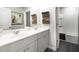 Bathroom featuring double sinks, white cabinets, gray walls, and a bathtub/shower with a white tile surround at 1221 Arnhem Dr, Hampton, GA 30228