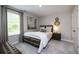 Bedroom featuring a dark metal and wood bedframe, neutral bedding, an accent wall hanging, and gray carpeting at 1221 Arnhem Dr, Hampton, GA 30228