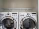 Up-close view of washer and dryer units with white shelving above for storage at 1006 Byron Sw Dr, Atlanta, GA 30310